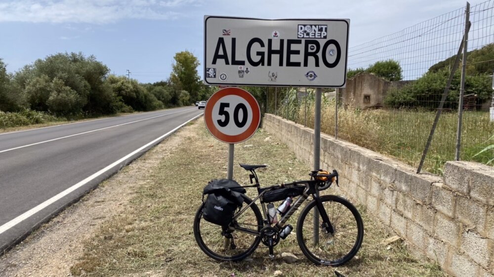 Bici sotto il cartello al confine di Alghero