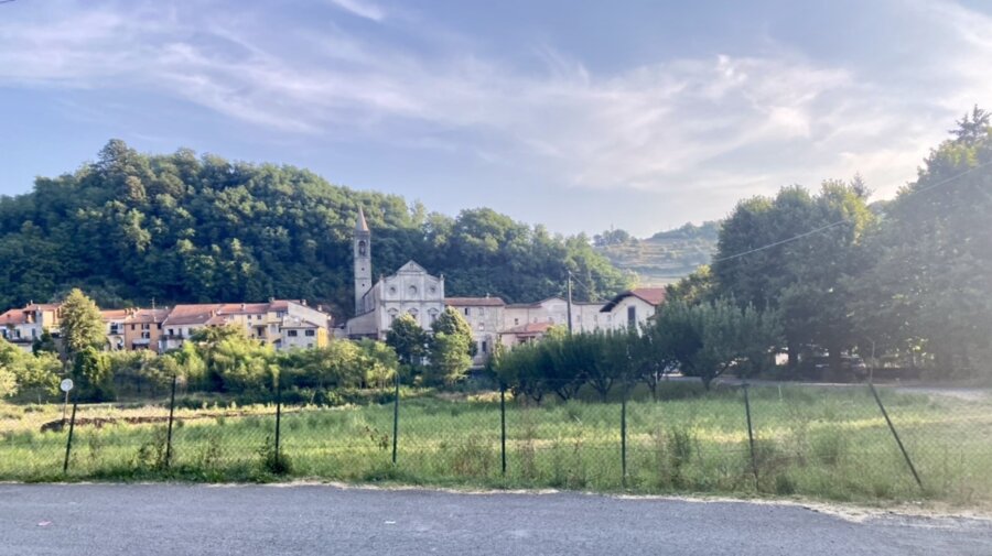 Chiesa in mezzo a un paesino ai piedi di una collina verde