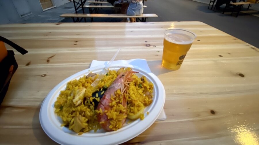 Paella in strada con birra alla spina su tavolone di legno