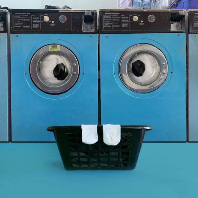 Due lavatrici con un cesto di biancheria davanti che mimano una faccia